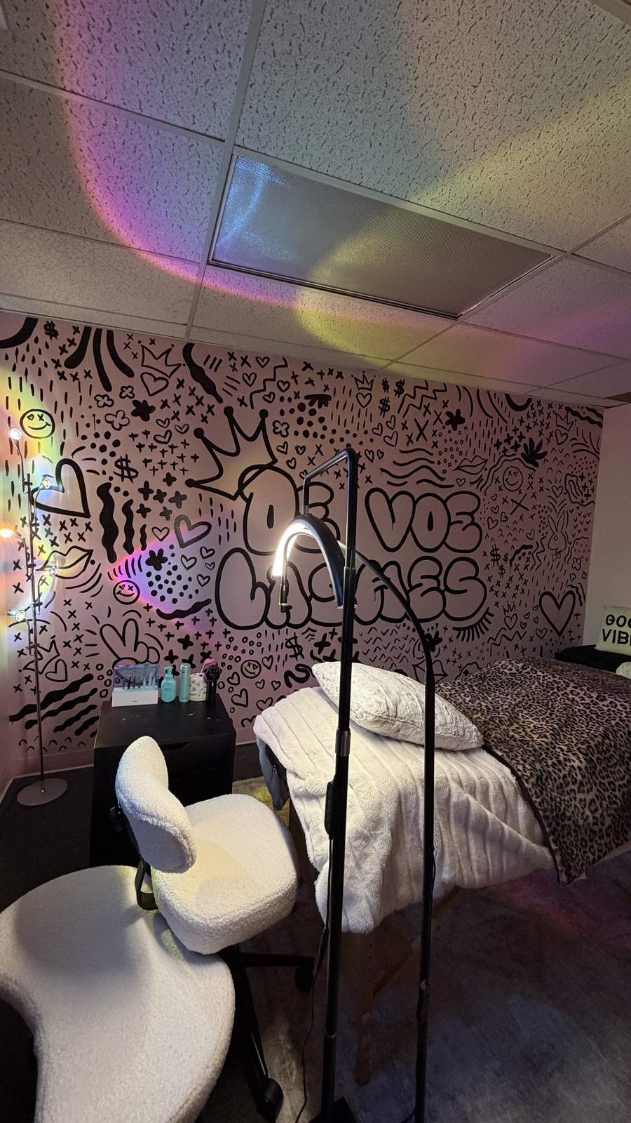 A lash bed with a leopard blanket in front of the black and white De Voe Lashes mural
